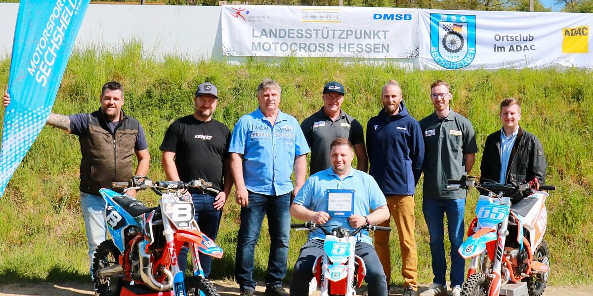 MSC Sechshelden Landessützpunkt Eröffnung 2026 Gruppe von Personen vor dem Banner „Landesstützpunkt Motocross Hessen“ beim MSC Sechshelden, mit drei Motocross-Motorrädern im Vordergrund.
