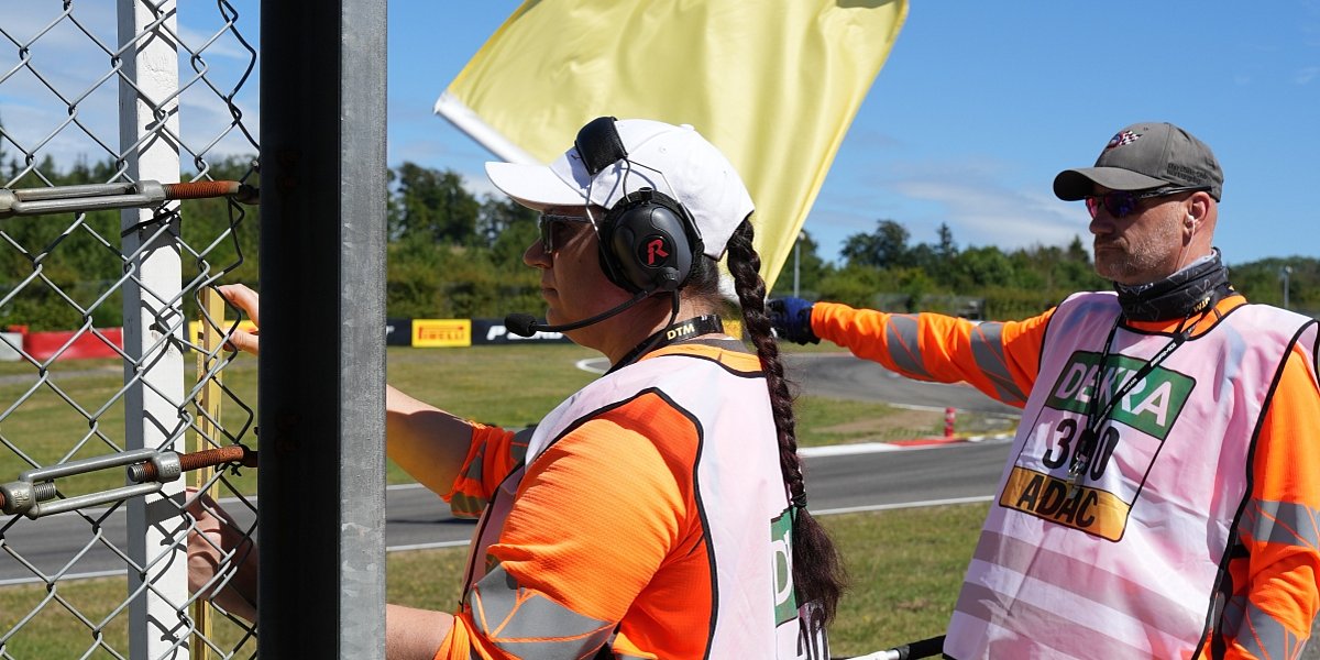 Sportwarte der Streckensicherung an einer Rennstrecke mit gelber Flagge