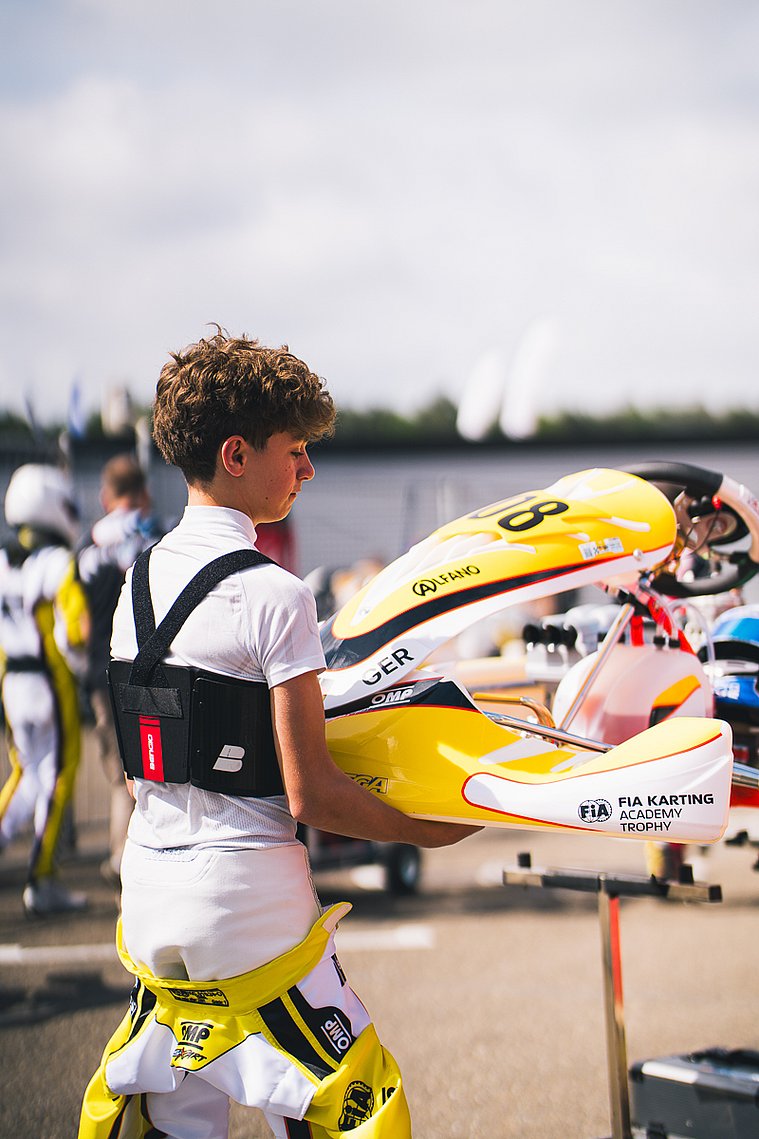 Stavros Tsotsos Francia trägt sein gelbes Kart im Fahrerlager der FIA Karting Academy Trophy zum Einsatzbereich.