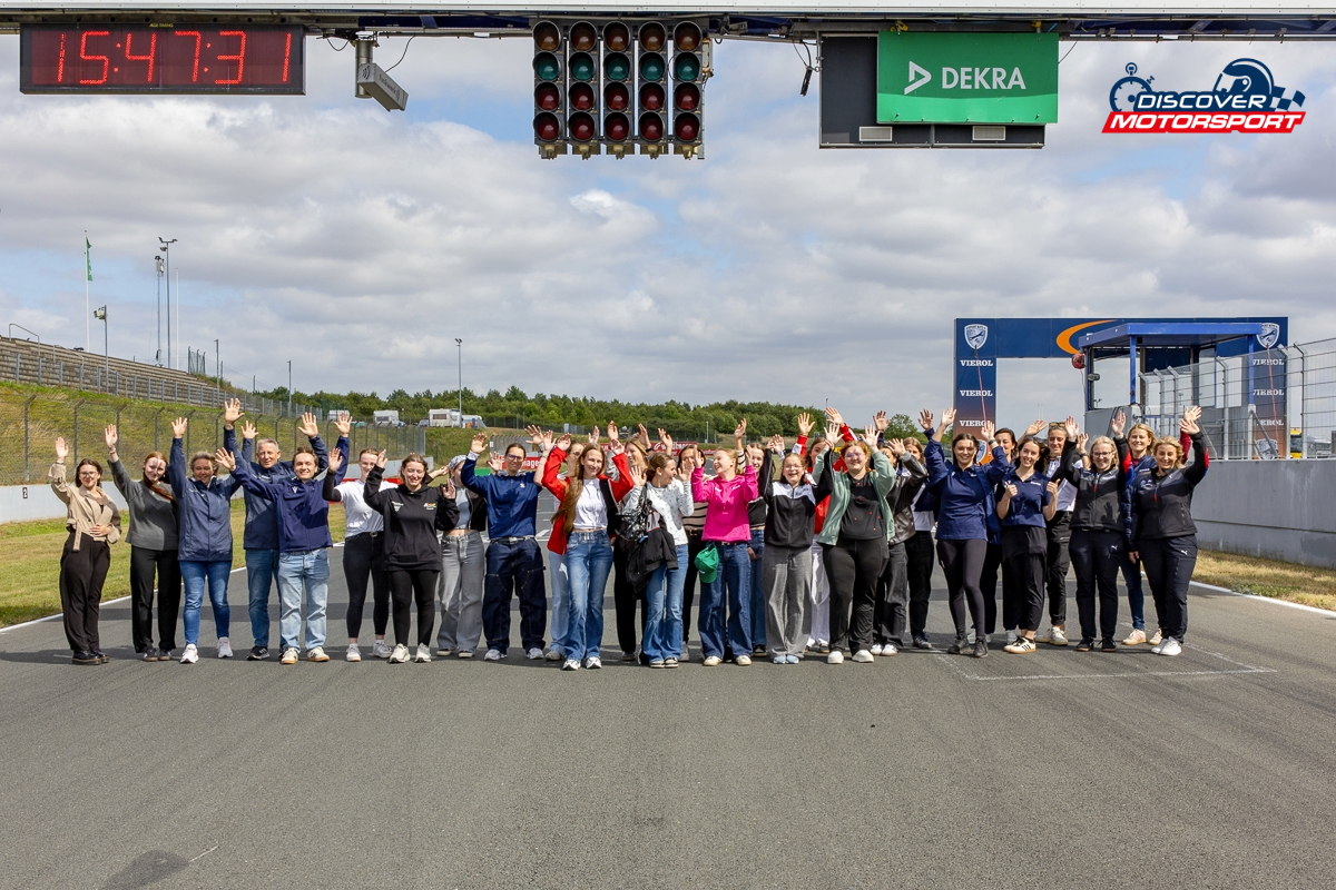 Discover Motorsport – Young Women's Edition 2026 in Oschersleben Teilnehmerinnen und Rednerinnen posieren gemeinsam für ein Gruppenfoto auf der Rennstrecke mit erhobenen Händen.